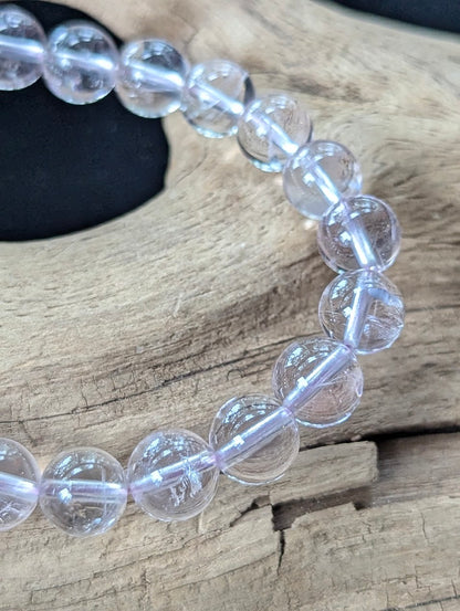 9mm Light Amethyst bracelet displayed on natural driftwood, showing glassy bead clarity and gentle purple tones.