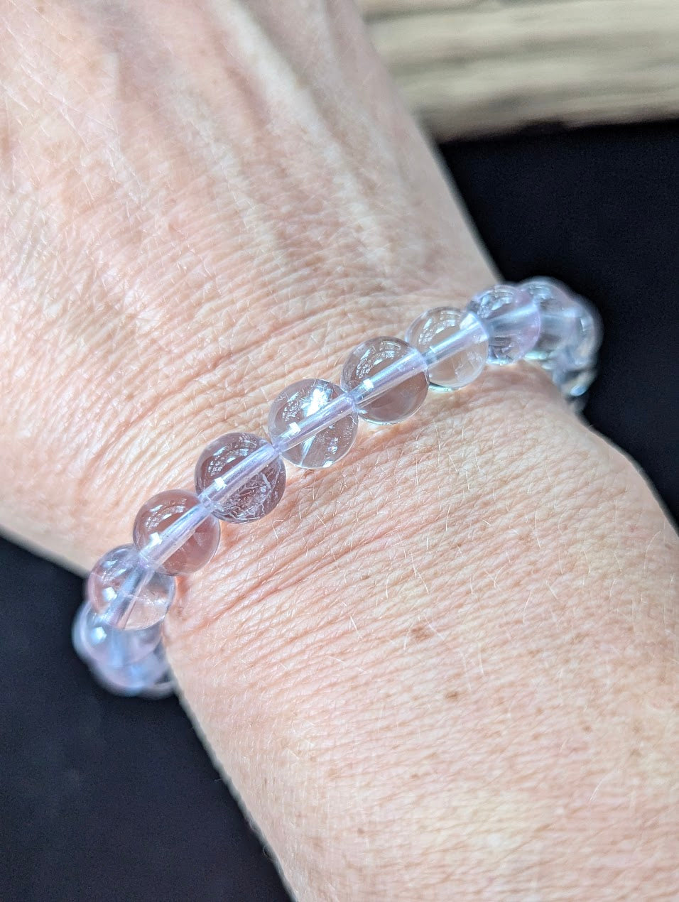 9mm Light Amethyst beaded bracelet worn on a wrist, catching the light to highlight its inner clarity.