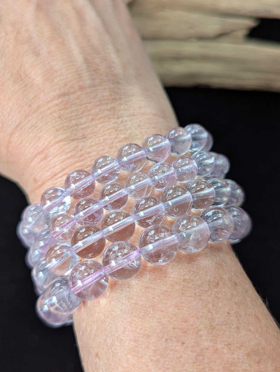 Multiple AA Grade Light Amethyst beaded bracelets stacked together on a wrist, demonstrating the high clarity and gentle lavender color across the different bead sizes.