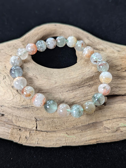 10mm Light Garden Quartz (Lodolite) Bracelet, showing striking clear beads with earthy inclusions on driftwood.