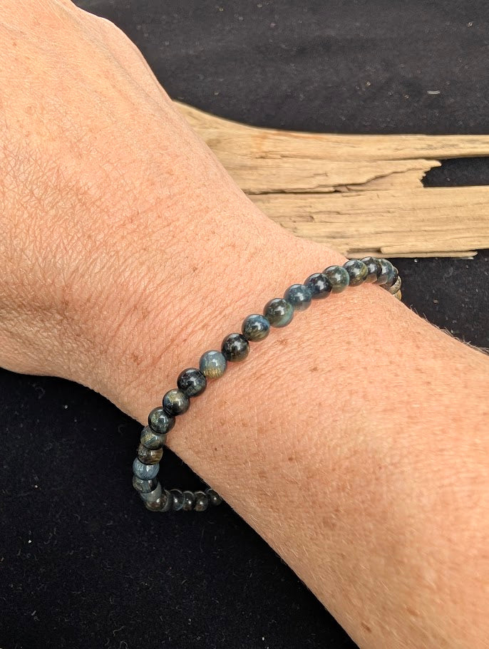 4mm polished Blue Tiger Eye beaded stretch bracelet worn on a wrist for delicate size scale.