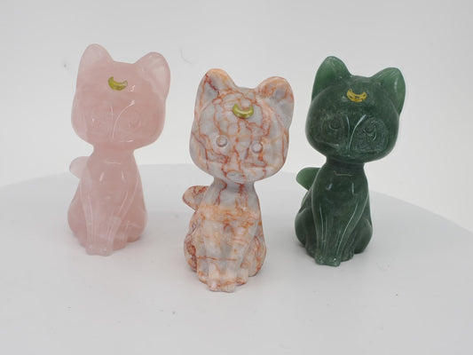 Three 3-inch hand-carved Luna cat figurines in Rose Quartz, Green Aventurine, and Red Vein Jasper with gilded moon details.
