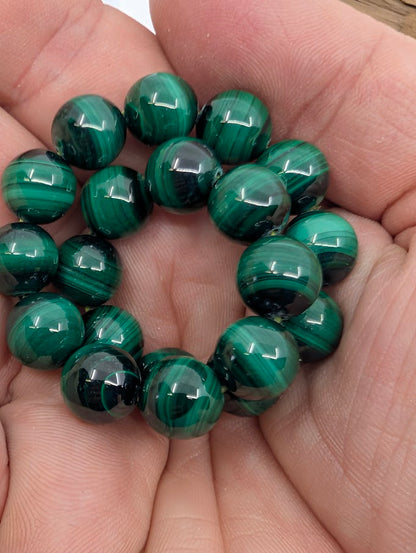 Handheld view of 10mm malachite bracelet showing deep green colour and bold natural banding