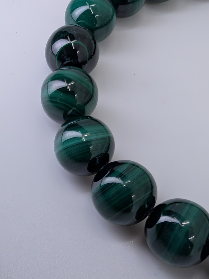 Macro shot of 10mm malachite beads showing fine natural banding and high polish