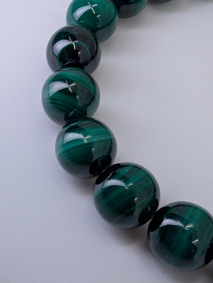Macro shot of 10mm malachite beads showing fine natural banding and high polish