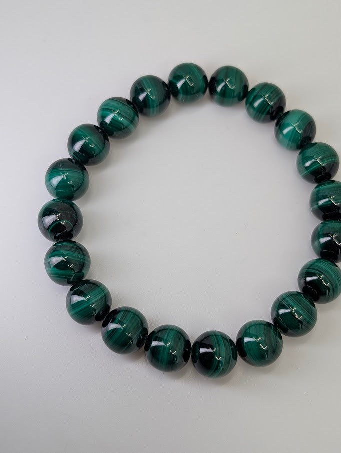 10mm malachite bracelet arranged in a circle showing glossy polish and deep green banding