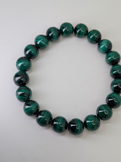 10mm malachite bracelet arranged in a circle showing glossy polish and deep green banding