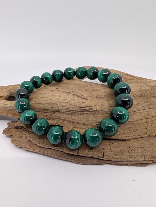 High quality 10mm malachite bracelet displayed on natural wood showing rich green colour and strong banding