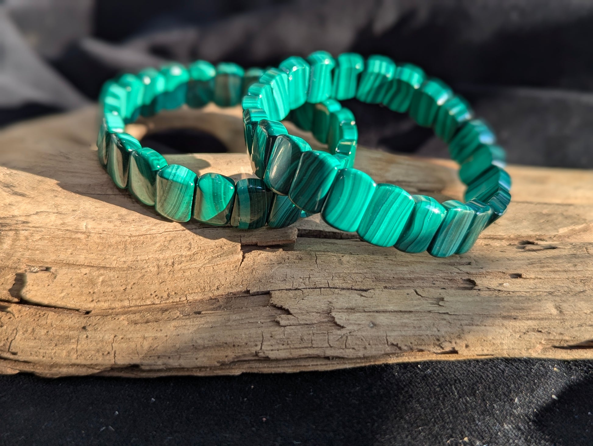 Polished banded malachite segmented bracelet featuring deep green natural mineral banding on wood display.