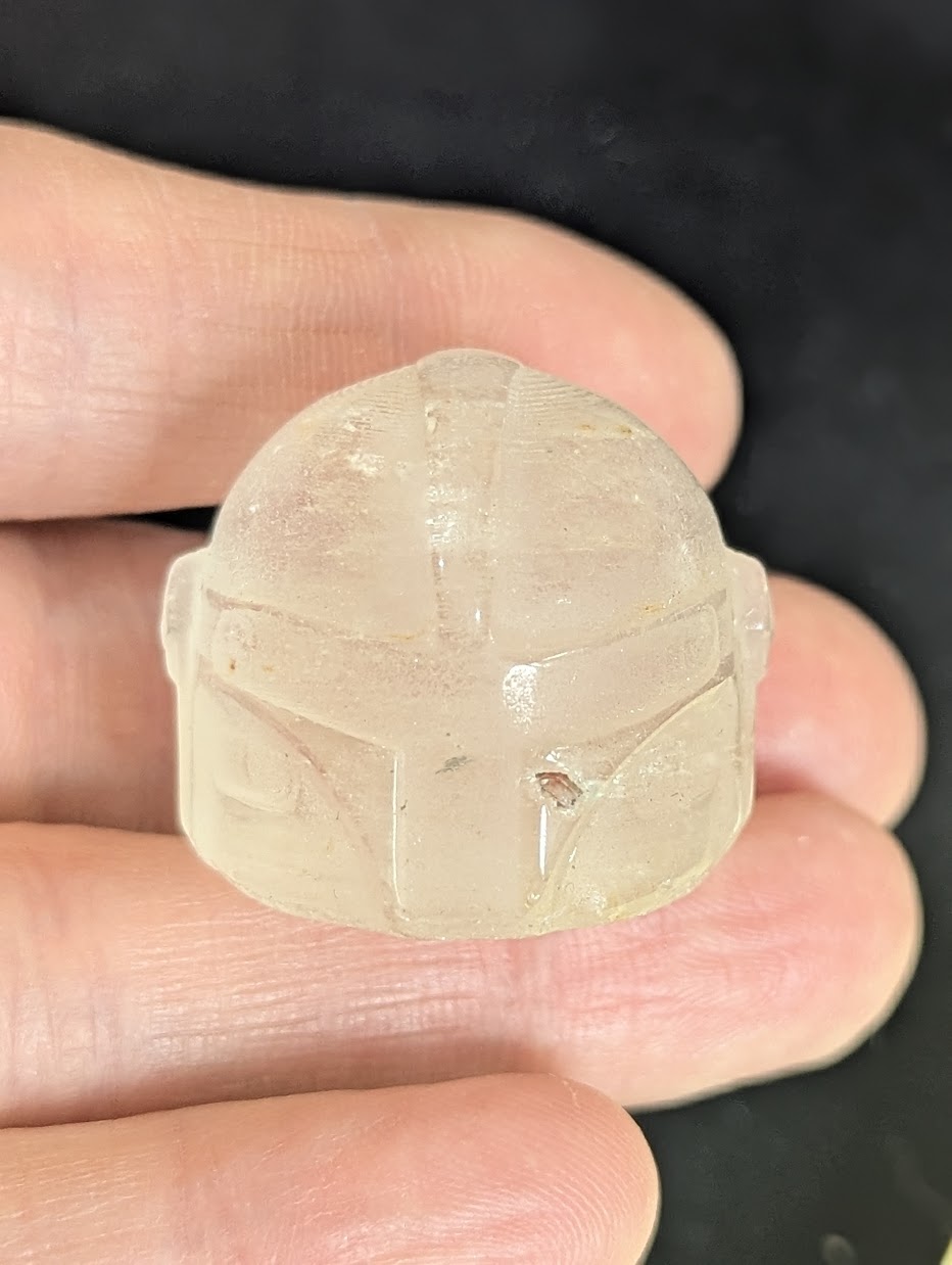 Front view of a 3cm Mandalorian helmet carved from natural Clear Quartz.