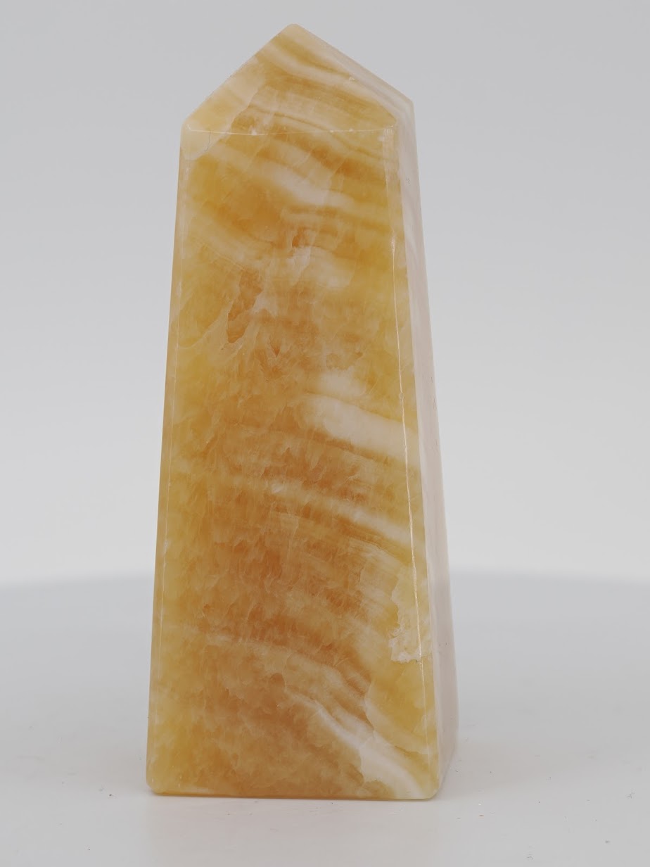 Polished Mango Calcite tower from Pakistan featuring vibrant golden-orange translucency and horizontal white mineral bands.
