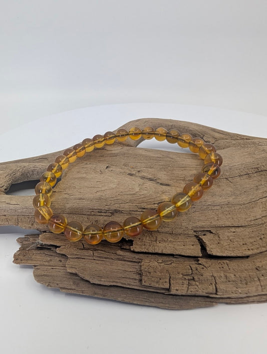 Mexican blue amber bracelet with 6mm beads displayed on driftwood