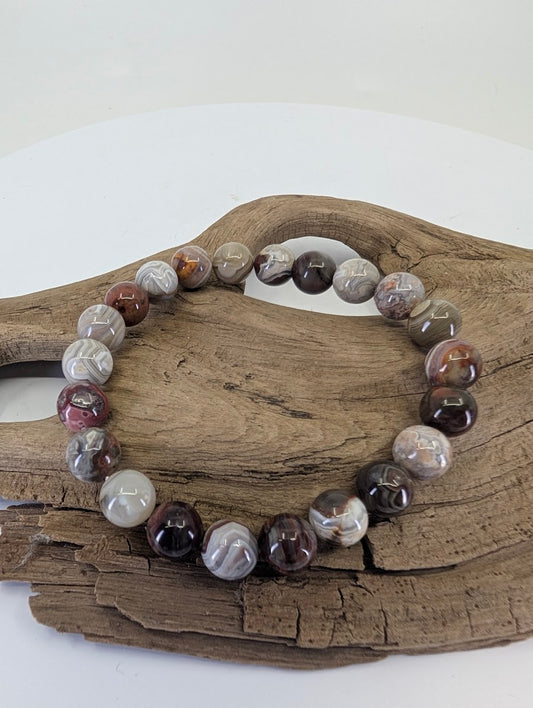 8mm Mexican Crazy Lace Agate bead bracelet showing intricate variegated banding on natural wood.