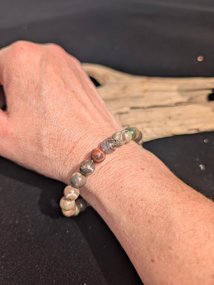 Natural sunlight on an 8mm multi-coloured earthy Money Agate stretch bracelet worn on a wrist.