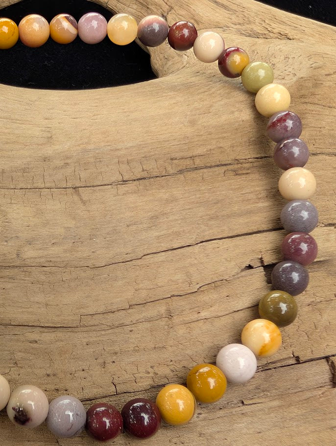 Macro close-up of 4mm polished Mookaite beads highlighting the high-gloss finish and multi-coloured earthy tones.