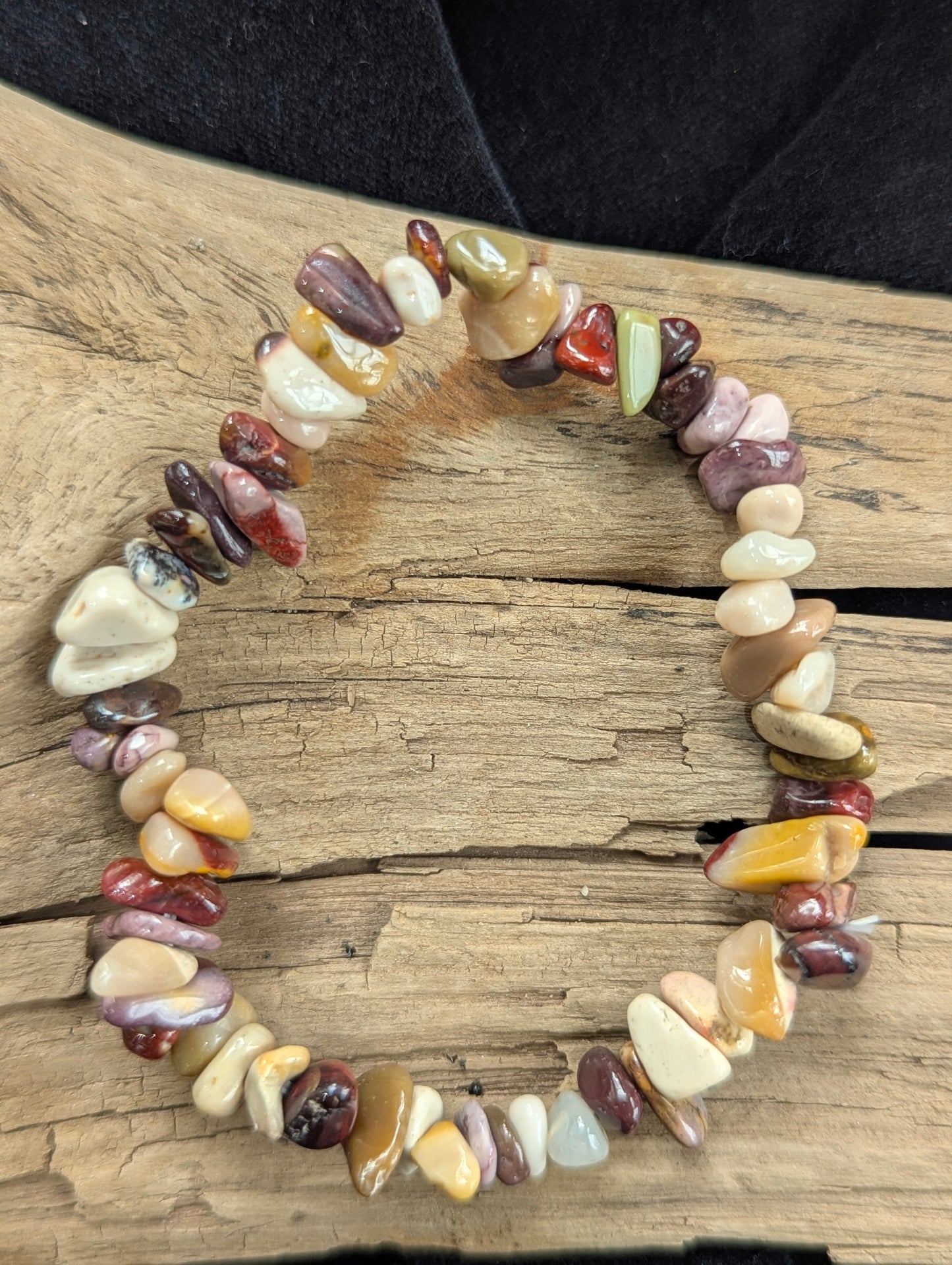 An all-natural Mookaite chip stretch bracelet from Western Australia beautifully displayed on natural driftwood.
