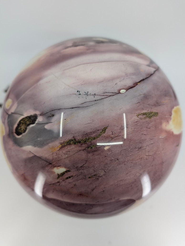 Top down view of a Mookaite crystal ball highlighting natural black dendrites and surface healing fractures.