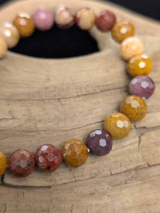 Macro close-up of 8mm faceted Mookaite beads highlighting geometric surface cuts and natural colour variations.