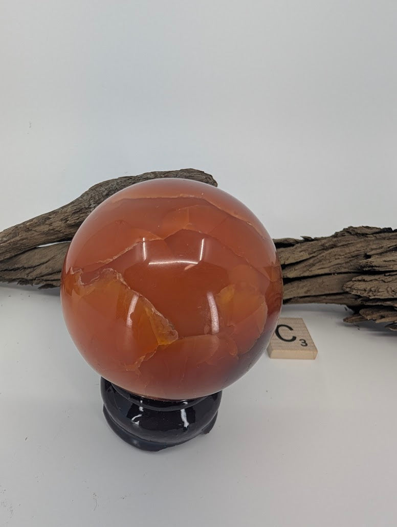 Translucent "Root Beer" red Mookaite sphere (60mm) on a stand.