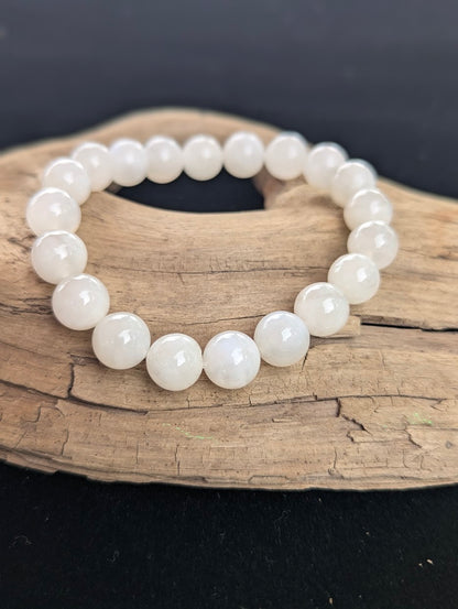 10mm cloudy white Moonstone bead bracelet from Sri Lanka displayed on driftwood.