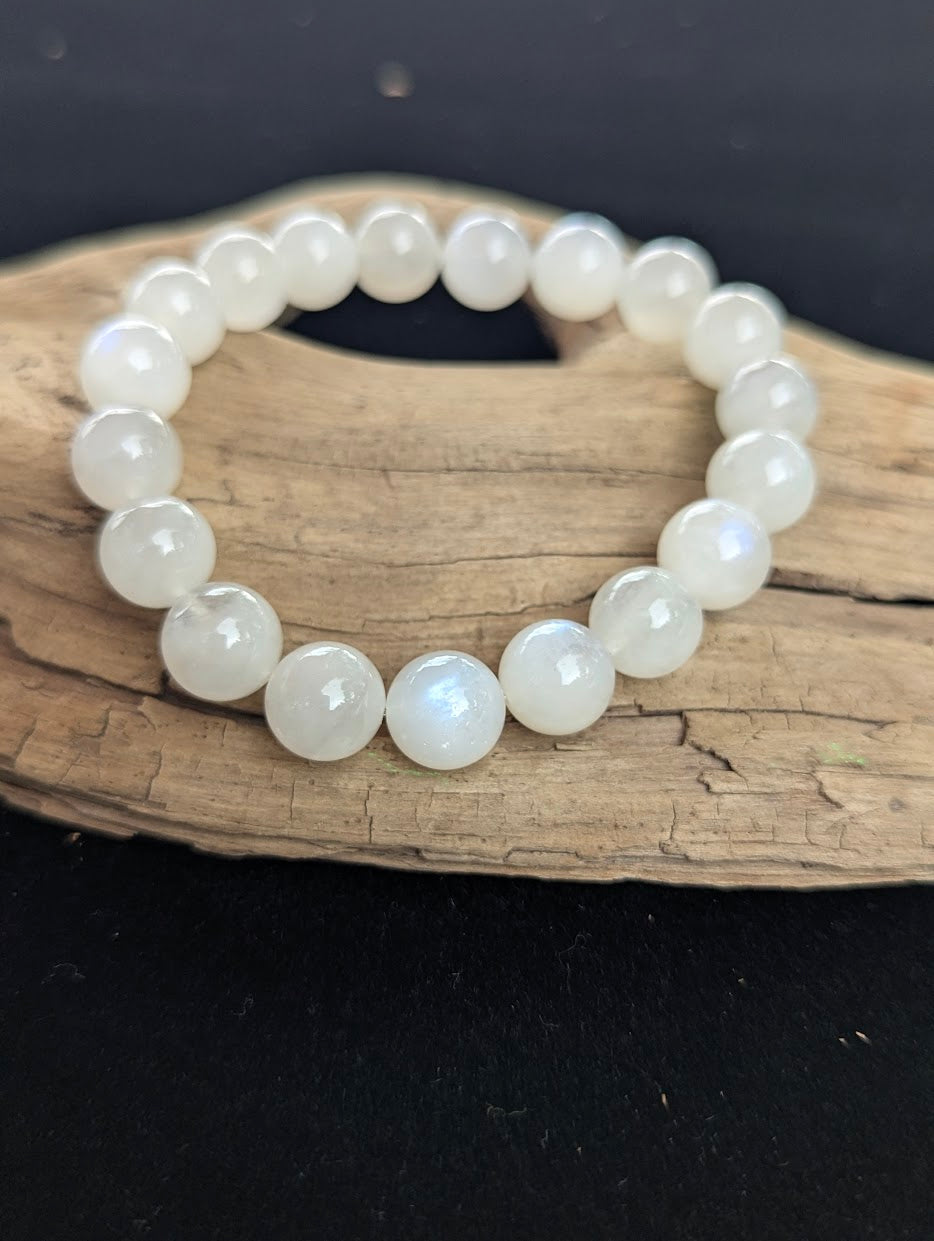 11mm cloudy white Moonstone bead bracelet from Sri Lanka displayed on driftwood.