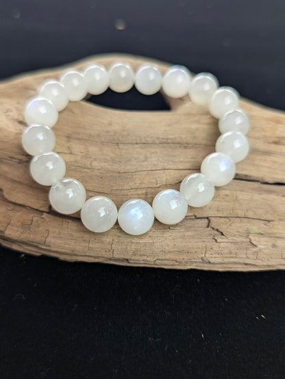 11mm cloudy white Moonstone bead bracelet from Sri Lanka displayed on driftwood.