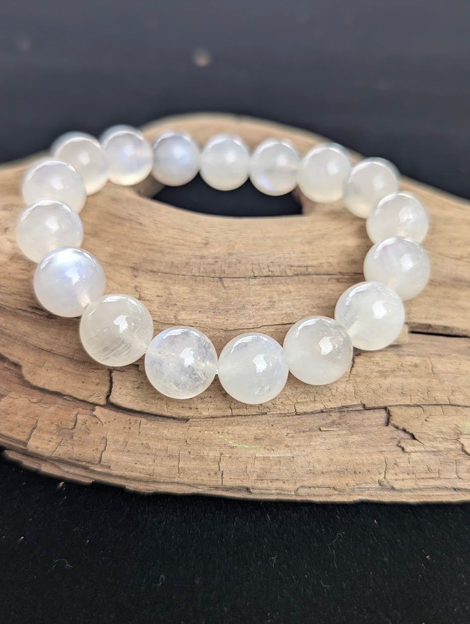 12mm cloudy white Moonstone bead bracelet from Sri Lanka displayed on driftwood.