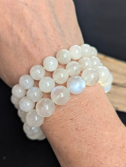 A stacked presentation of three Sri Lankan Moonstone bracelets in 10mm, 11mm, and 12mm sizes worn on a wrist.