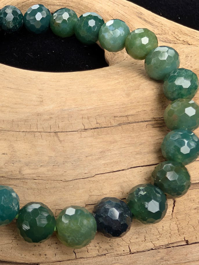 Macro close-up of 8mm faceted Moss Agate beads highlighting the geometric cut and the natural three-dimensional moss-like formations within the matrix.