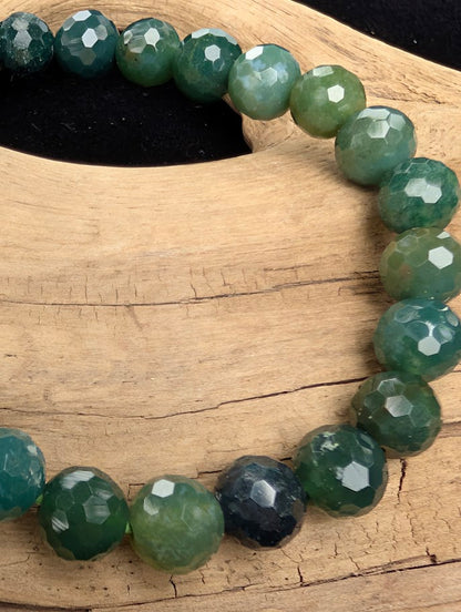 Macro close-up of 8mm faceted Moss Agate beads highlighting the geometric cut and the natural three-dimensional moss-like formations within the matrix.