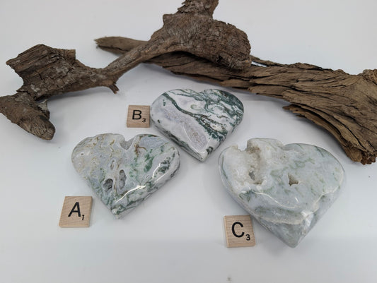 Group of three Moss Agate hearts labeled A, B, and C showing sparkling geode pockets.