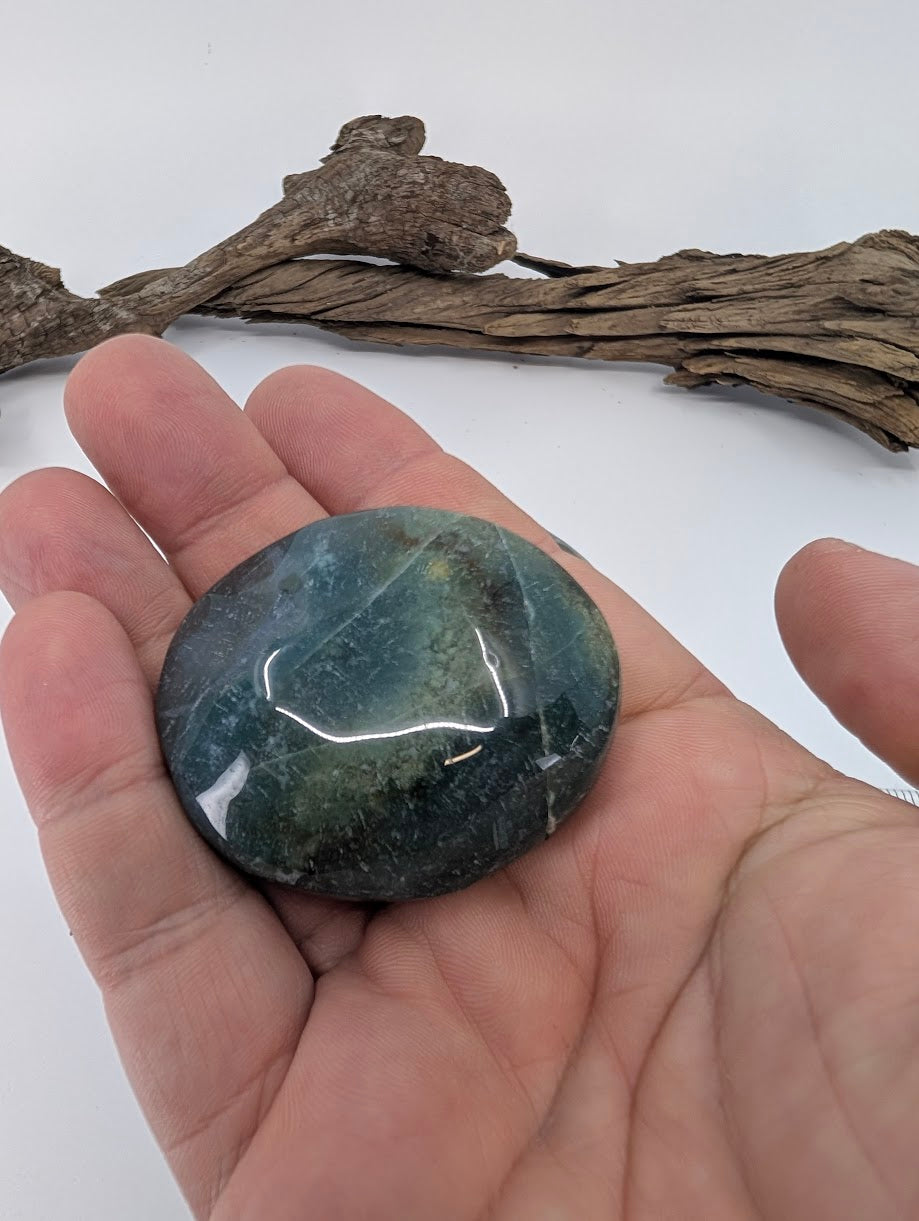 Moss Agate palm stone held in hand showing size, polish, and natural inclusions