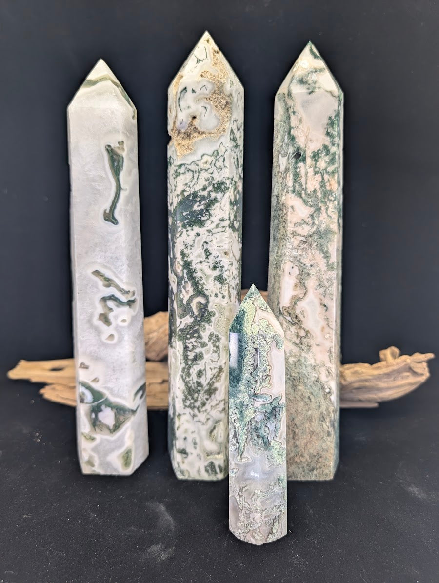 Group display of four Moss Agate towers of varying sizes and plume densities against a black background.