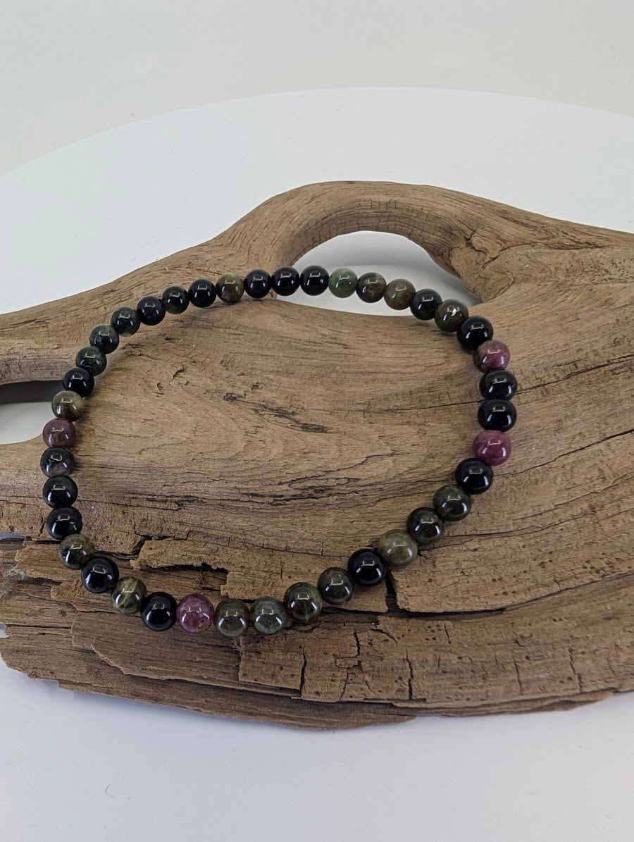 4.5mm Multi-Color Tourmaline bead bracelet from Brazil showing pink and green tones on natural wood.