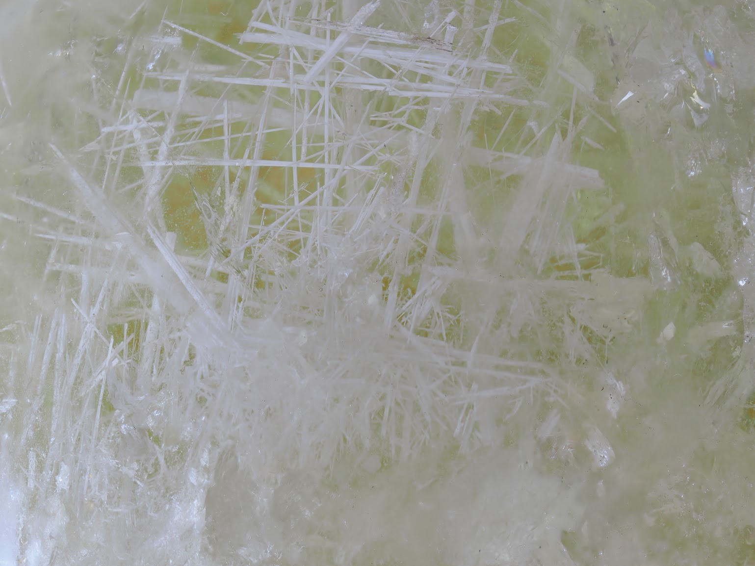 Extreme macro view of dense white acicular inclusions forming a lattice structure within the citrine quartz.
