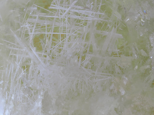 Extreme macro view of dense white acicular inclusions forming a lattice structure within the citrine quartz.