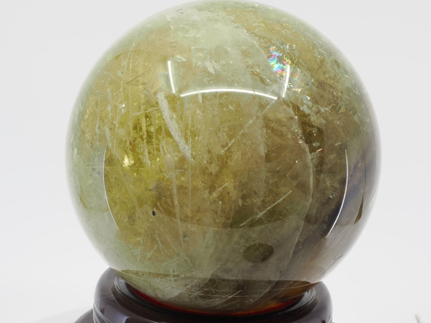 Natural Citrine sphere exhibiting a vibrant internal rainbow iris and golden transparency.