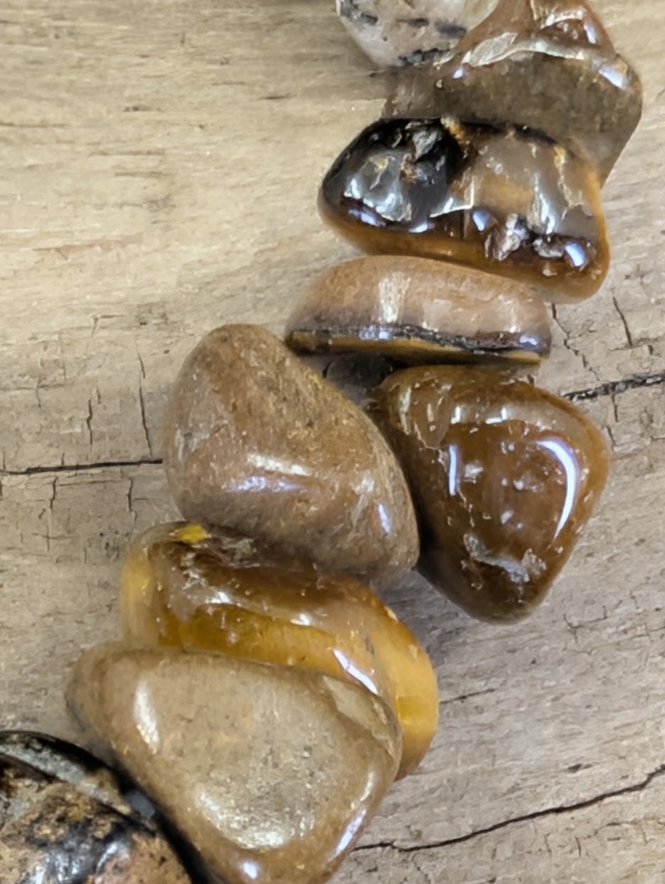 Close-up of tumbled Tiger’s Eye chips highlighting the silky luster and rich golden-brown earth tones.