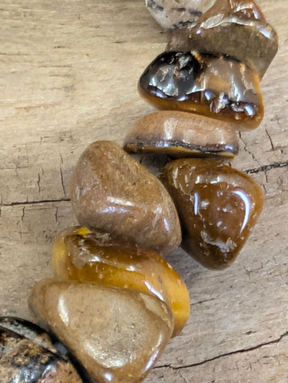 Close-up of tumbled Tiger’s Eye chips highlighting the silky luster and rich golden-brown earth tones.