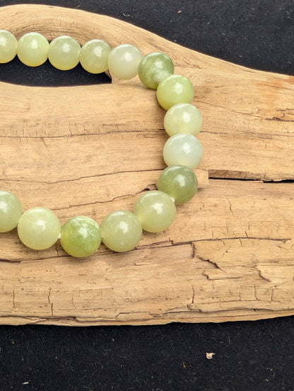 Macro close-up of 8mm polished New Jade Serpentine beads highlighting the high-gloss finish and milky pastel green translucency.