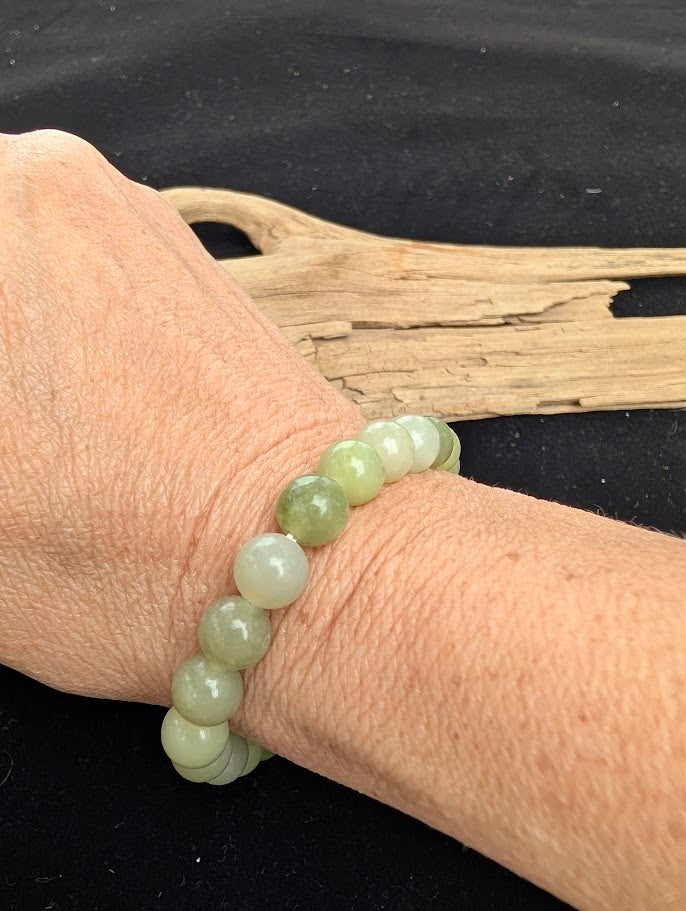 8mm polished New Jade Serpentine beaded stretch bracelet worn on a wrist for size scale.