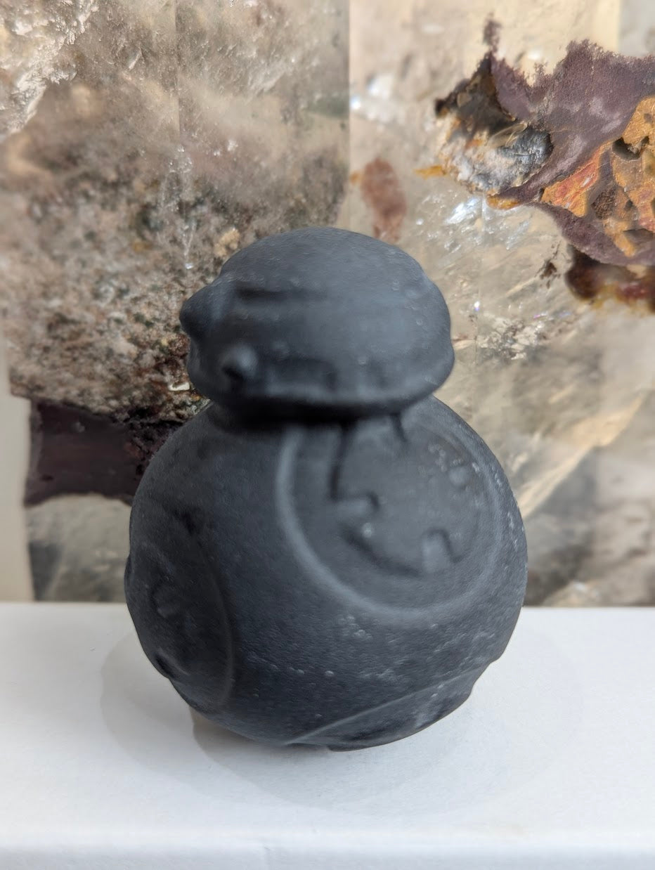 Side view of hand-carved obsidian BB-8 droid carving.