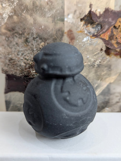 Side view of hand-carved obsidian BB-8 droid carving.