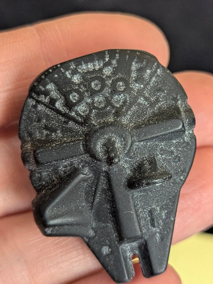 Top-down view of a matte black obsidian Millennium Falcon carving showing intricate ship mechanical details and natural scuffing.