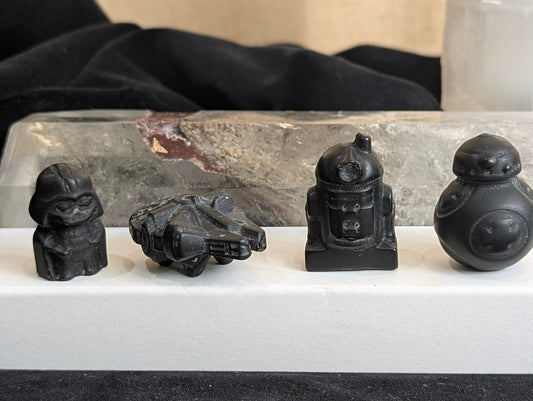 A 4-piece set of matte black obsidian carvings including Darth Vader, Millennium Falcon, R2-D2, and BB-8 on a white display.