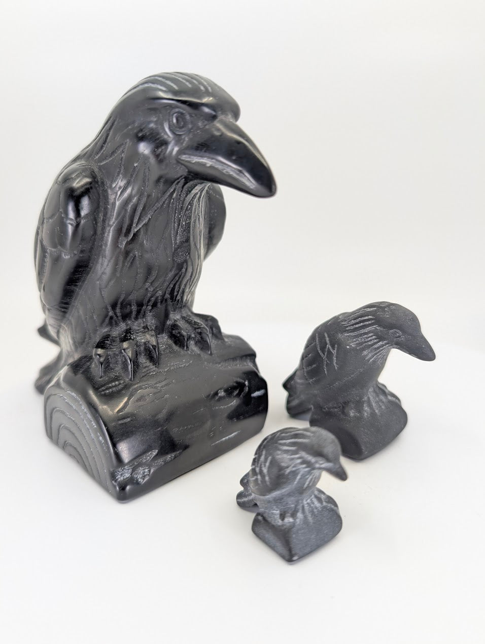 Group shot of three black obsidian raven carvings in small, medium, and large sizes