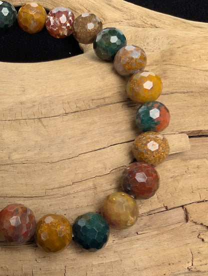 Macro close-up of 8mm faceted Ocean Jasper beads highlighting geometric surface cuts and natural multi-coloured spherical fossil-like patterns.