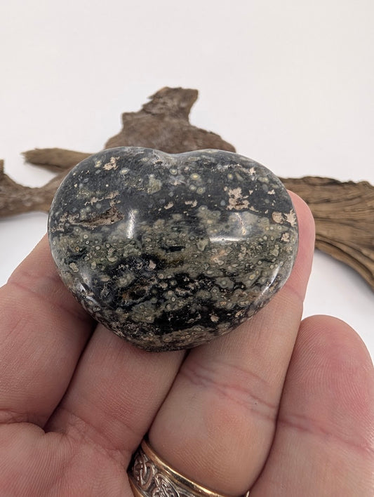 Hand holding a 60g Black Ocean Jasper heart showing orbicular patterns.