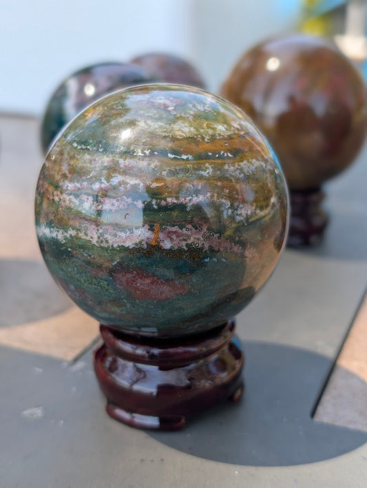 Close-up of 63mm Ocean Jasper sphere showing deep green and red orbicular chalcedony patterns.