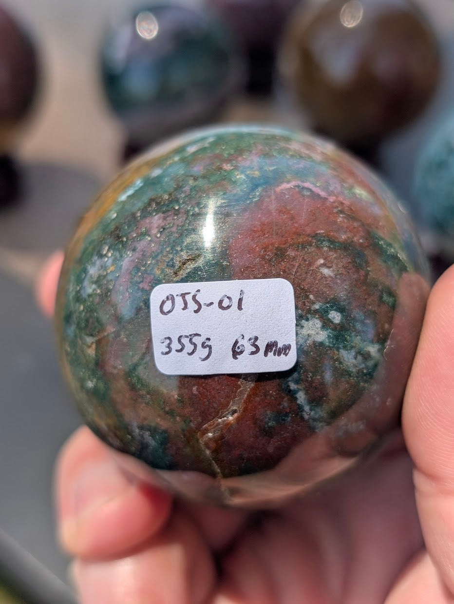 Side profile of 63mm polished Ocean Jasper sphere from Madagascar showing continuous mineral structure.